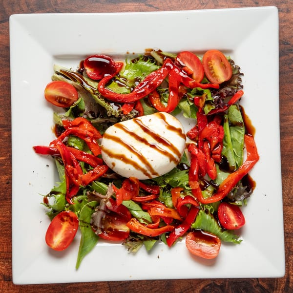 Grilled mozzarella with balsamic glaze, roasted red peppers, cherry tomatoes, and mixed greens.